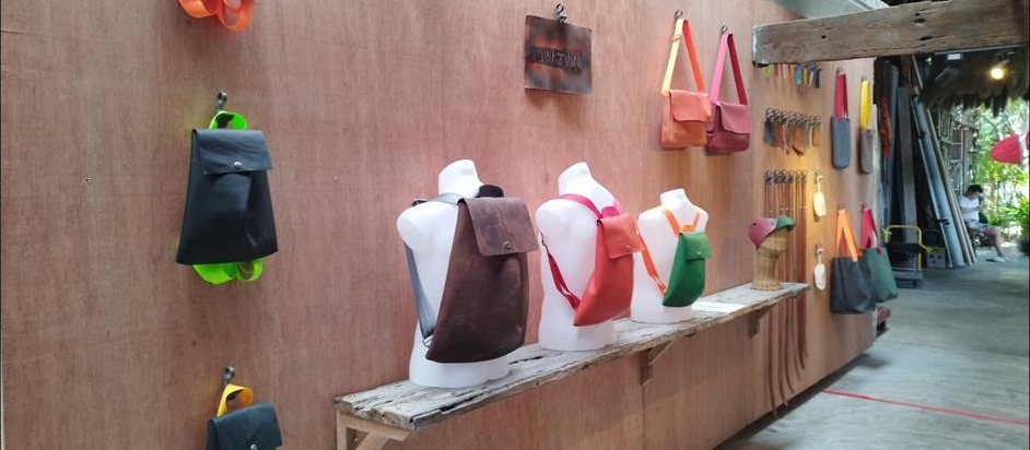 The DWNTWN atelier wall on Soi Mangkorn, bags hung on coloured straps